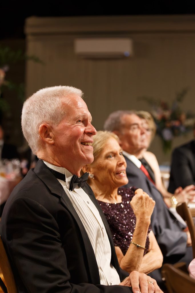 Dr. Peter Kindschuh and his wife Gayle Kindschuh enjoy a presentation from their children in his honor. 